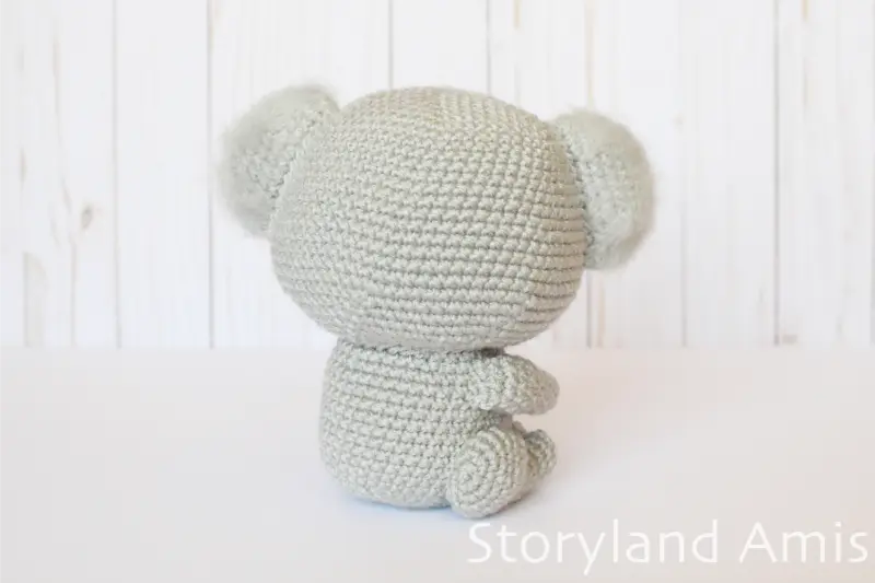 An amigurumi koala is shown from the back as it sits on a white table.