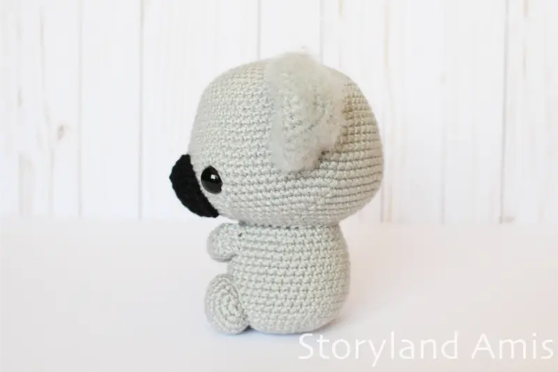 An amigurumi koala sits on a white table.