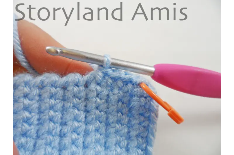 A close-up of a border being crocheted along the edge of a crocheted headdress for an amigurumi doll.