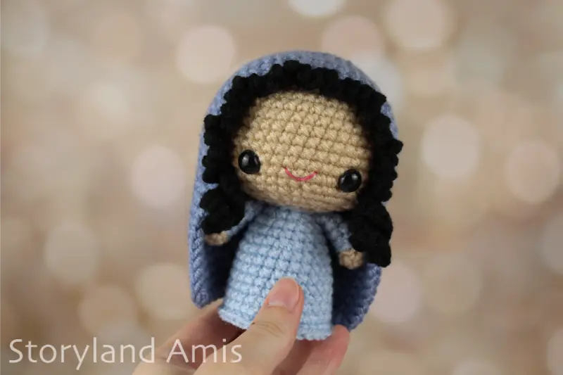 A hand holds an amigurumi Mary doll for a nativity set.