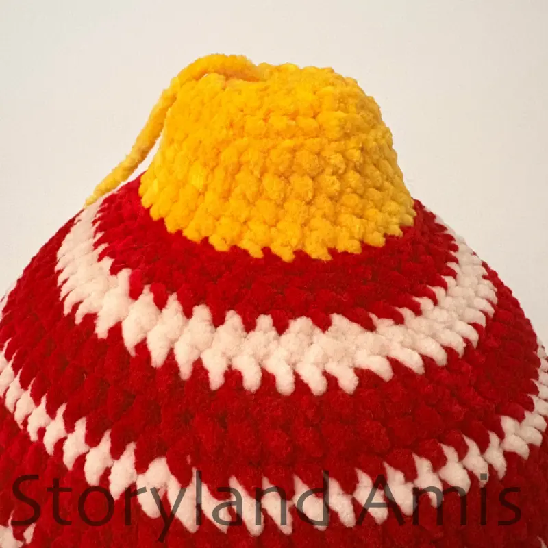 A close-up of the top of a crocheted amigurumi Christmas ornament.