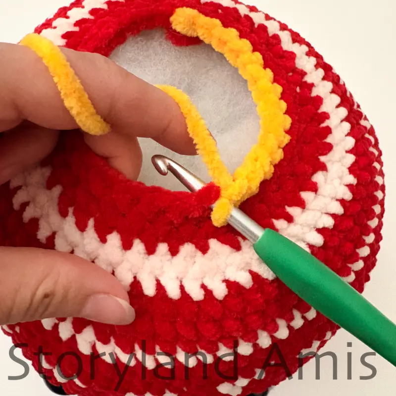 A close-up shows a green crochet hook inserted in a stitch on the top of a round crocheted ball.