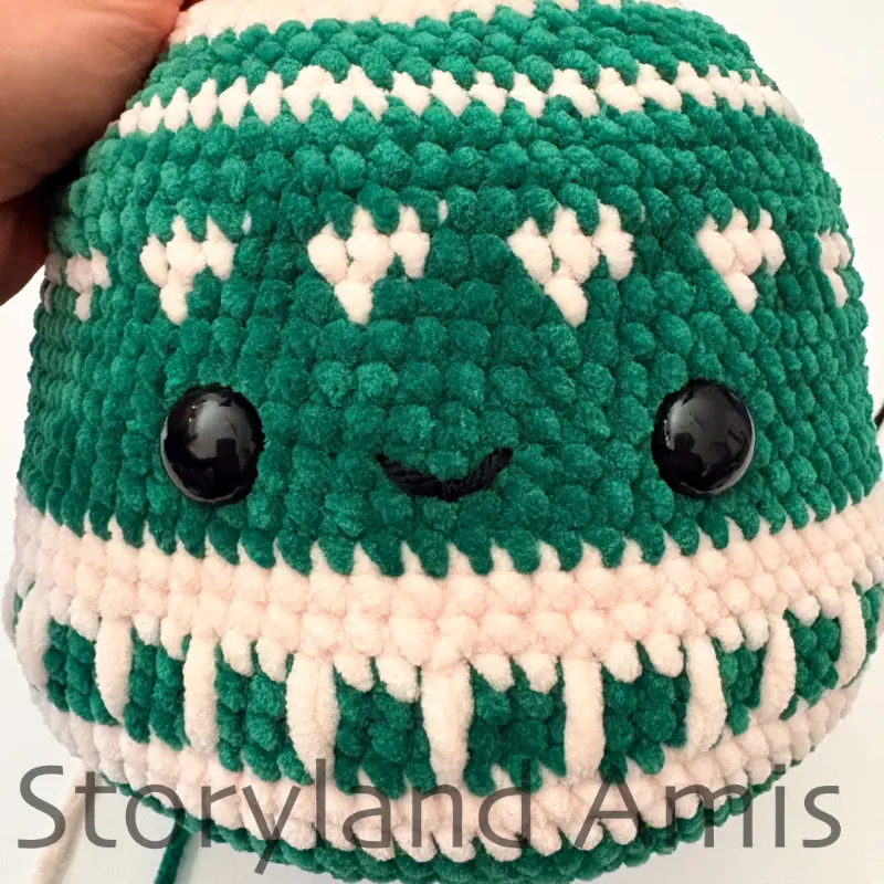 A close-up of the front of an amigurumi ornament showing the eyes and mouth.