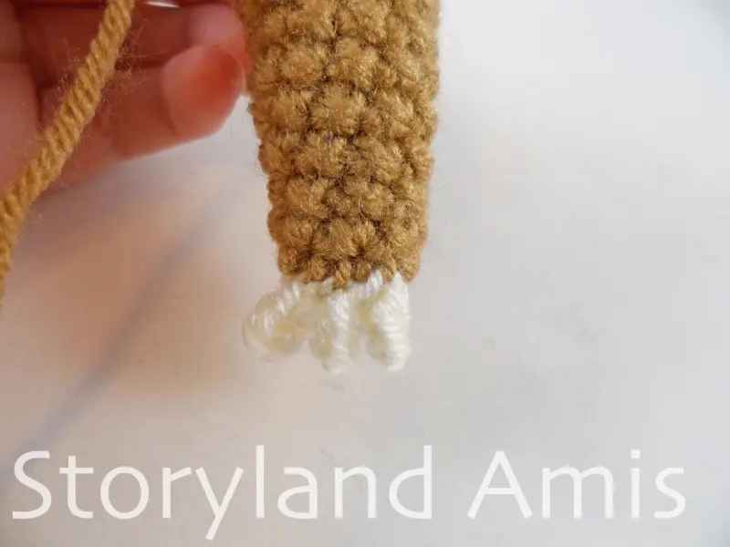 A close-up of the bottom of a crocheted sloth arm.