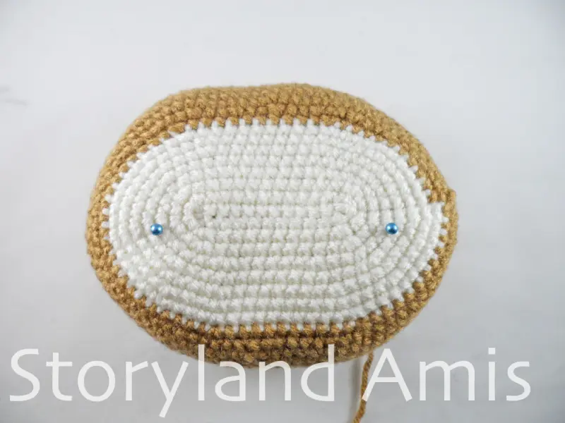 A cream and brown crocheted oval lies on a white table.