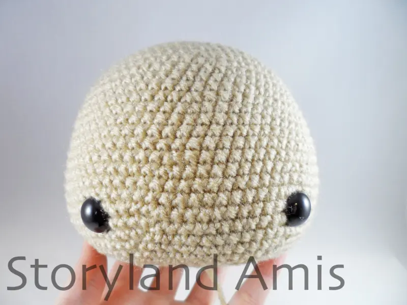 A hand holds up a crocheted dog head.