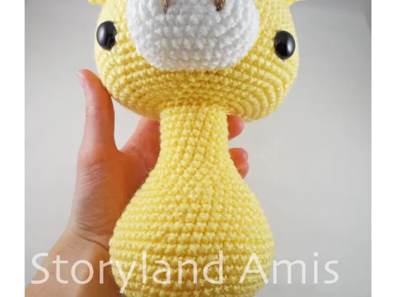 A close-up of the neck and body of a partially finished amigurumi giraffe toy.