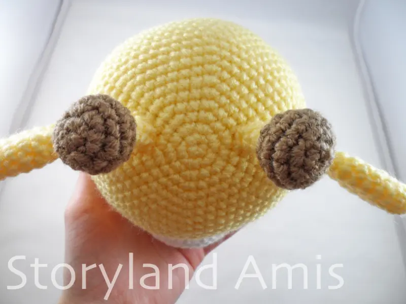 A close-up of the top of an amigurumi giraffe's head shown from above.