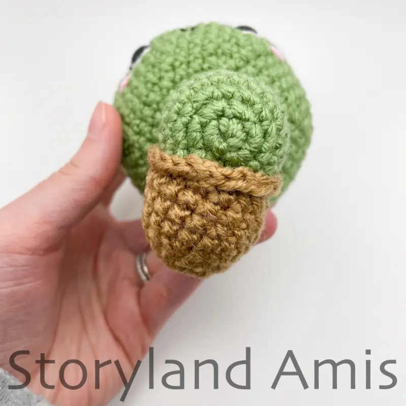 The underside of a partially finished tortoise held by a hand.