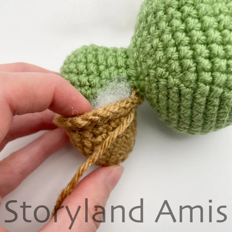 A close-up of a hand stuffing the shell of an amigurumi tortoise.