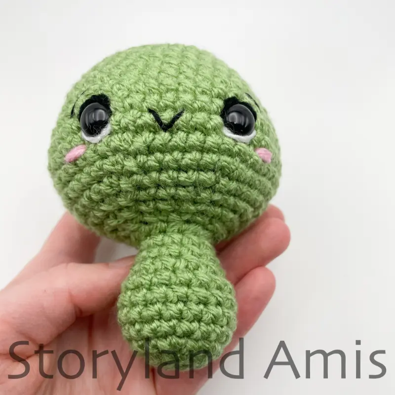 A hand holds a partially finished amigurumi tortoise.