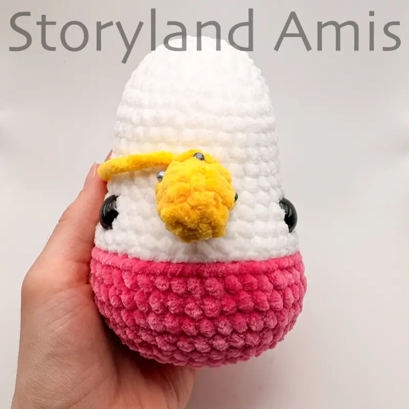 The front of an amigurumi unicorn's head with a crocheted yellow horn pinned between the eyes.