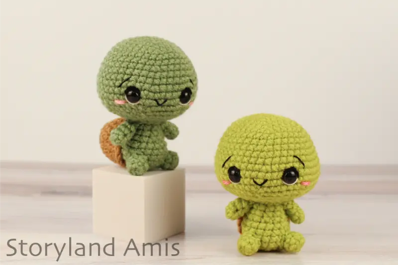 Two crocheted amigurumi tortoises sit on a wooden table.