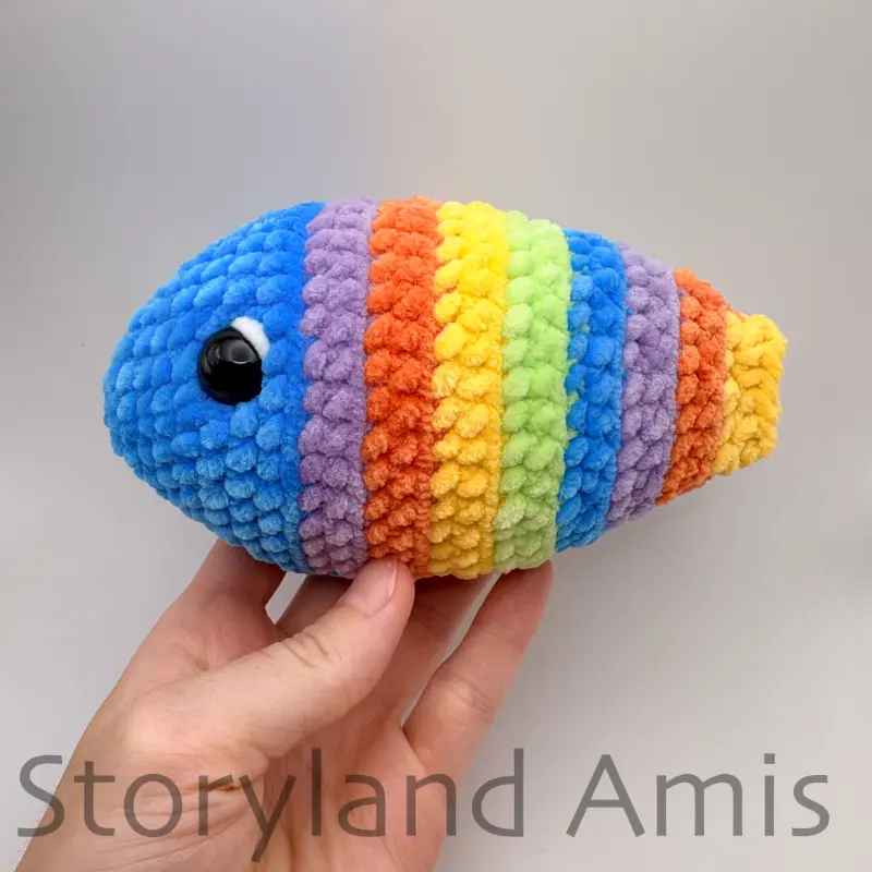 A hand holds up a partially finished amigurumi fish.