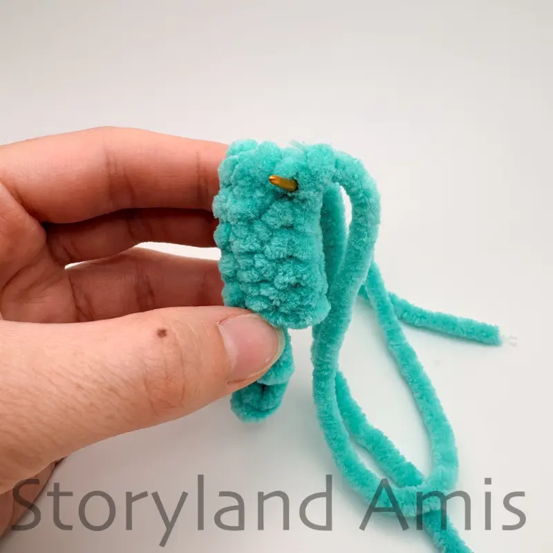 A hand holds a small, crocheted fish fin.