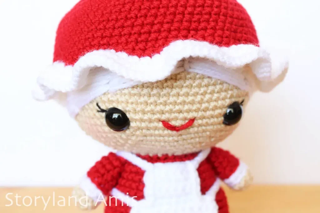 A close-up of a crocheted Mrs. Claus amigurumi doll.