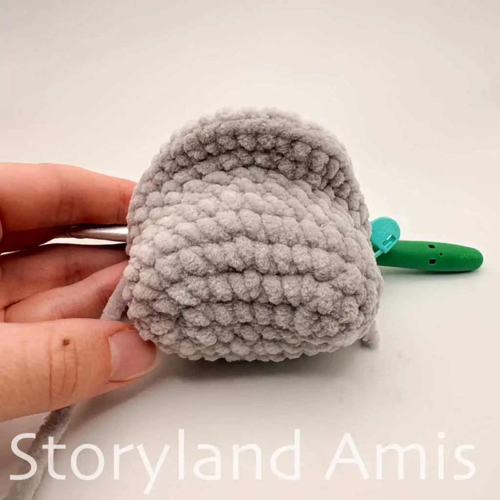 A partially finished crocheted amigurumi manatee sits against a white background.